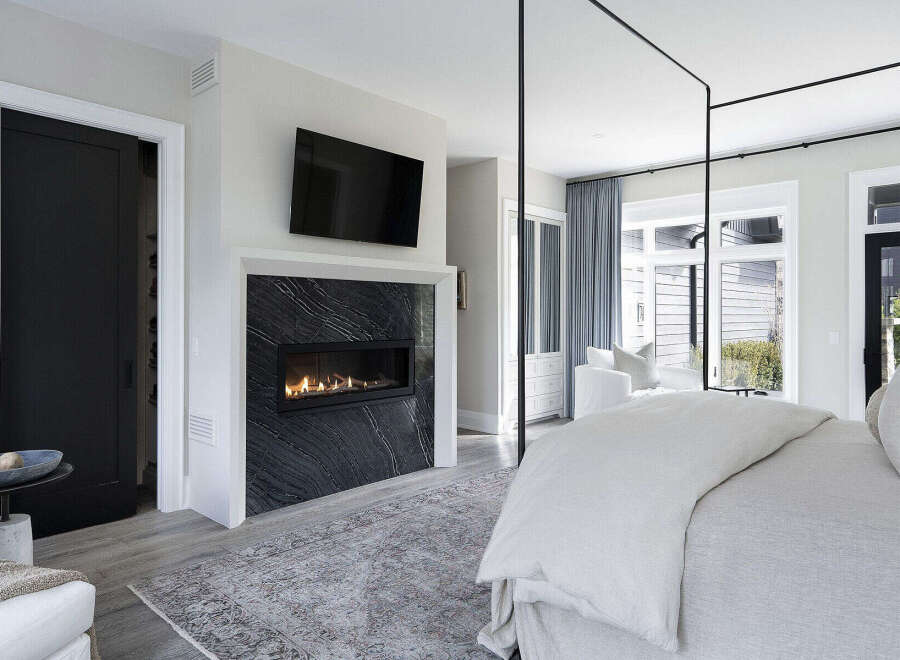 Experience luxury living in this stunning bedroom, featuring a modern fireplace and a sleek, contemporary design.
