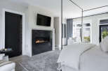 Experience luxury living in this stunning bedroom, featuring a modern fireplace and a sleek, contemporary design.