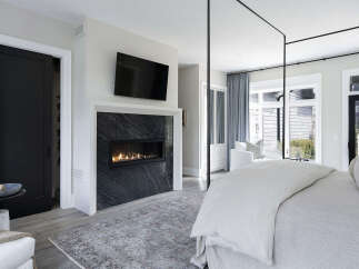 Experience luxury living in this stunning bedroom, featuring a modern fireplace and a sleek, contemporary design.