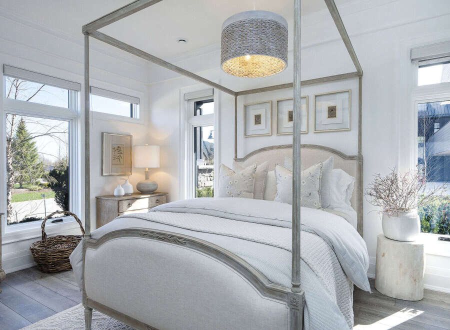 Step into a serene bedroom retreat, where natural light floods through expansive windows, illuminating the elegant four-poster bed.