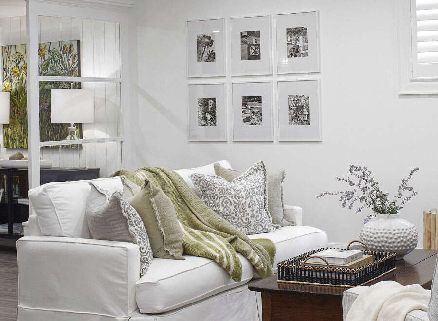 This inviting living space features a comfortable white sofa adorned with decorative pillows and a cozy green throw blanket.