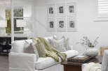 This inviting living space features a comfortable white sofa adorned with decorative pillows and a cozy green throw blanket.