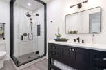 Step into luxury with this stunning bathroom featuring a modern black vanity and a sleek glass shower enclosure.