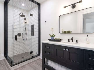 Step into luxury with this stunning bathroom featuring a modern black vanity and a sleek glass shower enclosure.