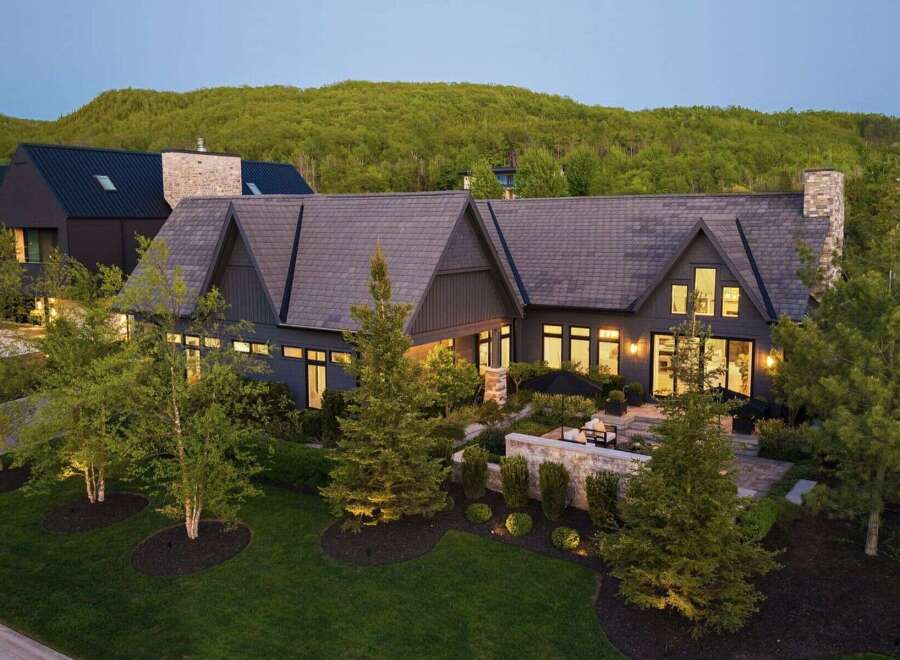 Experience luxury living in this stunning modern home, nestled against a backdrop of lush green hills.