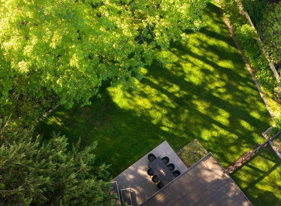Enjoy the tranquility of this stunning property, featuring a lush green lawn and a shaded patio perfect for outdoor dining.