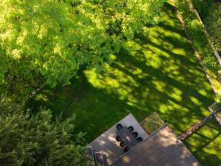 Enjoy the tranquility of this stunning property, featuring a lush green lawn and a shaded patio perfect for outdoor dining.