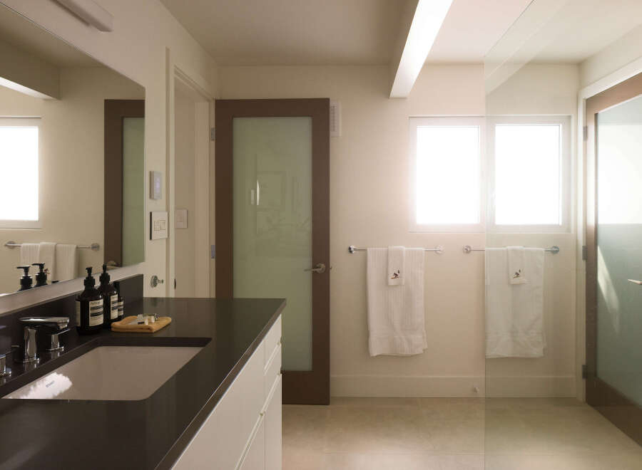 This modern bathroom boasts a sleek design with a dark countertop and a pristine white sink.