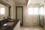 This modern bathroom boasts a sleek design with a dark countertop and a pristine white sink.
