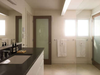 This modern bathroom boasts a sleek design with a dark countertop and a pristine white sink.