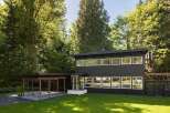 This stunning modern home boasts a sleek, dark exterior and an abundance of natural light.