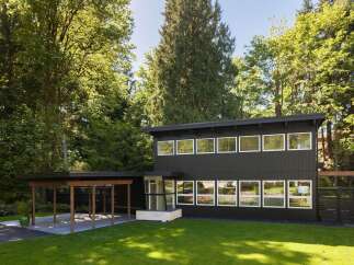 This stunning modern home boasts a sleek, dark exterior and an abundance of natural light.
