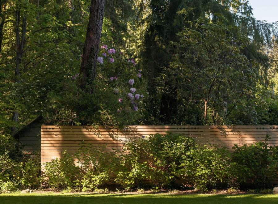 Discover the tranquility of this stunning property, featuring lush greenery and a beautifully crafted wooden fence.