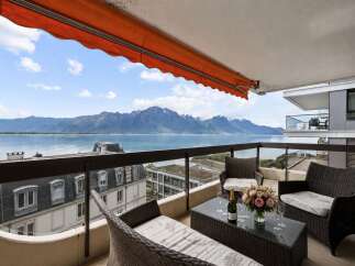 Enjoy breathtaking views from this stunning balcony overlooking a serene lake and majestic mountains.