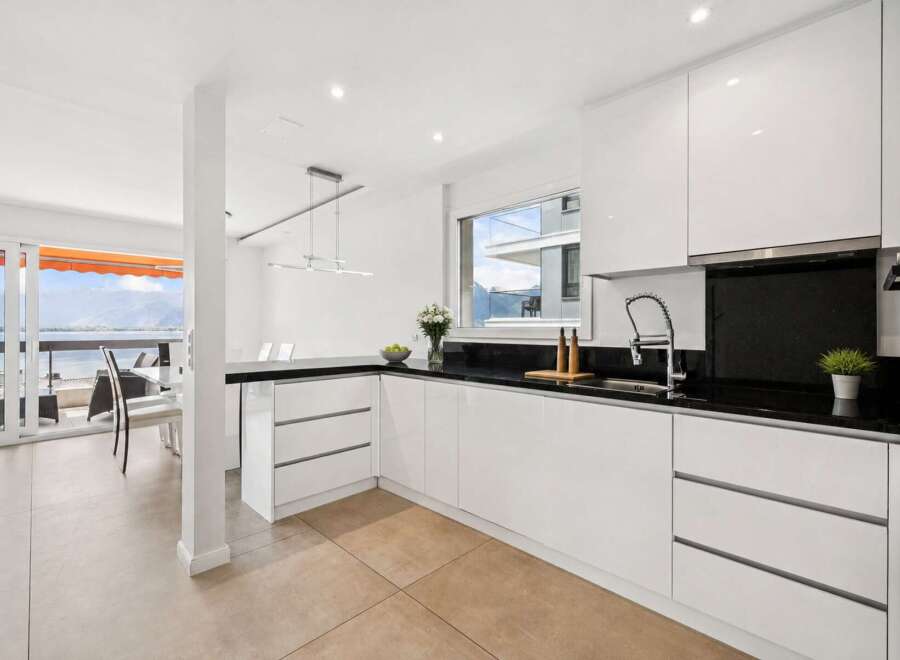 This stunning kitchen boasts sleek, modern design with pristine white cabinetry and a contrasting black countertop.