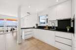 This stunning kitchen boasts sleek, modern design with pristine white cabinetry and a contrasting black countertop.