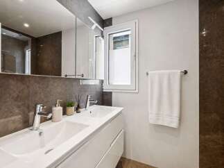 Step into a modern bathroom oasis! This stylish space features a sleek white vanity with dual sinks, complemented by a large mirror and elegant lighting.