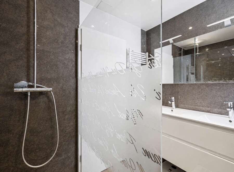 Step into a modern bathroom oasis! This stunning space features a sleek shower with a glass door, a stylish vanity, and a large mirror.