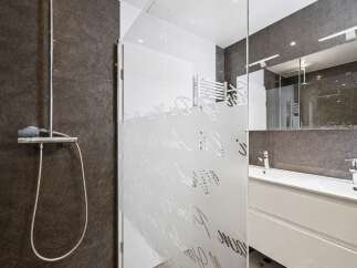 Step into a modern bathroom oasis! This stunning space features a sleek shower with a glass door, a stylish vanity, and a large mirror.