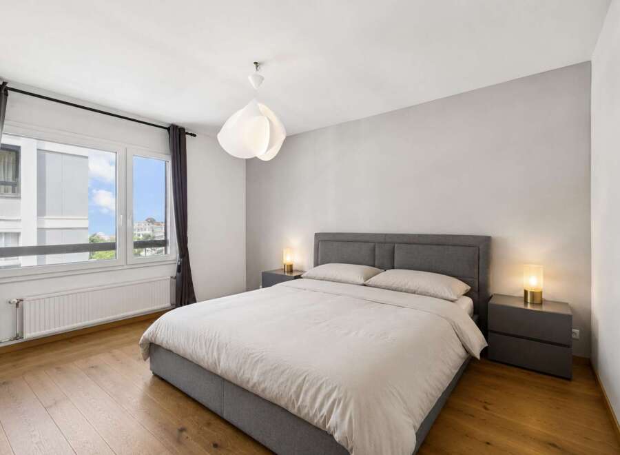 This modern bedroom offers a serene retreat with its neutral color palette and ample natural light.