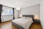 This modern bedroom offers a serene retreat with its neutral color palette and ample natural light.