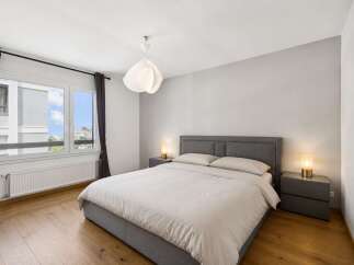 This modern bedroom offers a serene retreat with its neutral color palette and ample natural light.