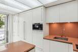 This modern kitchen boasts sleek, white cabinetry and a built-in coffee machine, perfect for the discerning homeowner.
