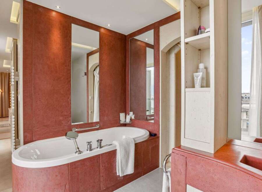Indulge in luxury within this exquisite bathroom, featuring a stunning oval bathtub and elegant red tile accents.