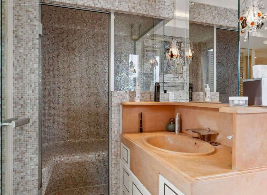 Step into luxury with this stunning bathroom featuring a mosaic-tiled shower and a unique, built-in sink.