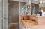 Step into luxury with this stunning bathroom featuring a mosaic-tiled shower and a unique, built-in sink.