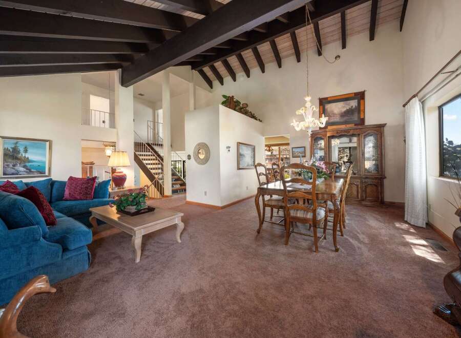 Step into luxury with this stunning property, showcasing a spacious living area with high ceilings and exposed beams.