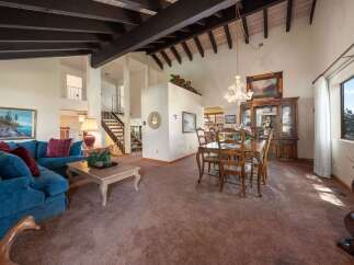 Step into luxury with this stunning property, showcasing a spacious living area with high ceilings and exposed beams.