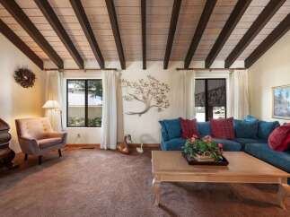 Step into this inviting living space, featuring a stunning wood-beamed ceiling and a cozy ambiance.