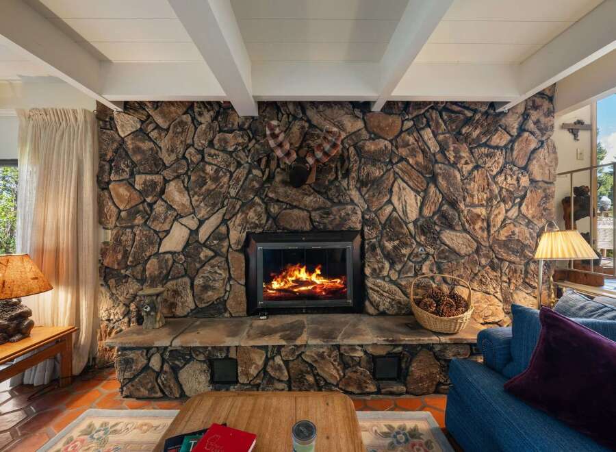 Experience the warmth of this stunning property, featuring a rustic stone fireplace as the centerpiece of the living area.