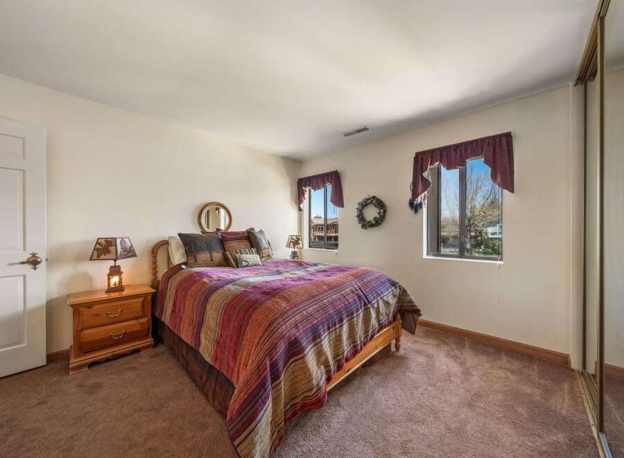 This cozy bedroom features a comfortable bed with a colorful patterned comforter, perfect for a relaxing night's sleep.