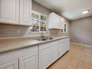This charming kitchen boasts bright white cabinetry and a neutral countertop, creating a clean and inviting space.