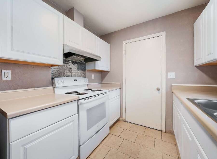 This kitchen features bright white cabinetry and appliances, creating a clean and inviting atmosphere.