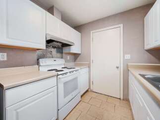 This kitchen features bright white cabinetry and appliances, creating a clean and inviting atmosphere.