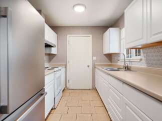 Step into this bright and inviting kitchen, featuring pristine white cabinetry and ample counter space.