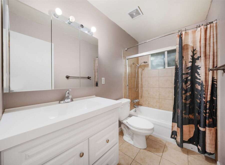 This bathroom features a bright and airy design with a clean white vanity and a large mirror.