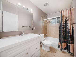 This bathroom features a bright and airy design with a clean white vanity and a large mirror.