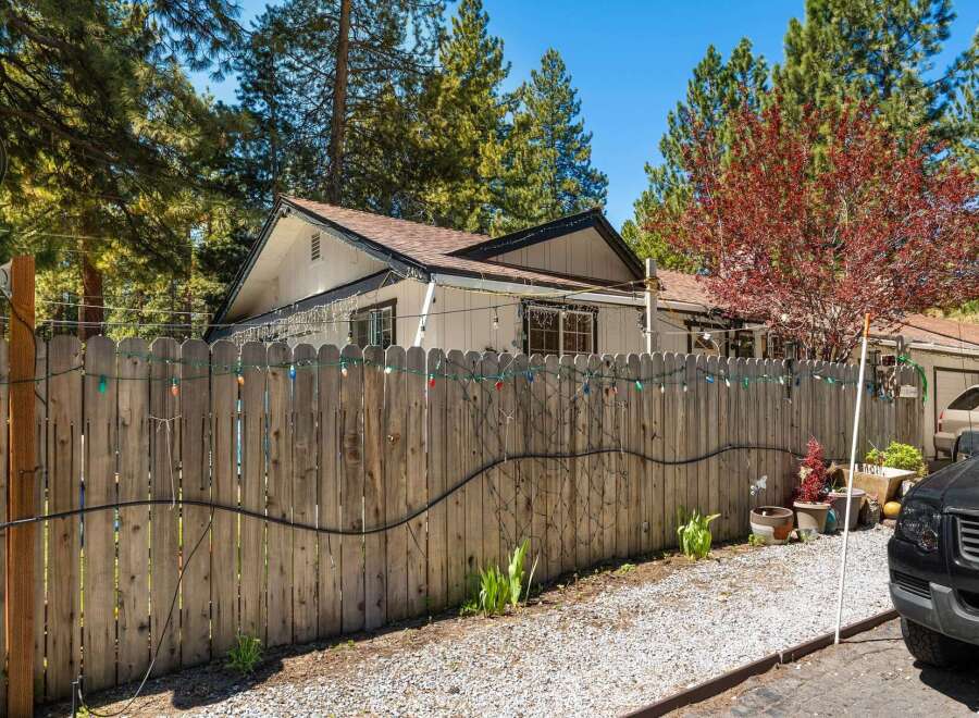 Discover the charm of this inviting property, featuring a well-maintained wooden fence adorned with festive lights.