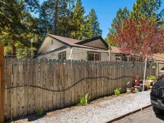 Discover the charm of this inviting property, featuring a well-maintained wooden fence adorned with festive lights.