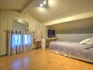 This charming bedroom features a cozy, inviting atmosphere with its warm wooden floors and unique architectural details.
