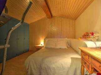 This cozy bedroom features a unique wooden ceiling and walls, creating a warm and inviting atmosphere.