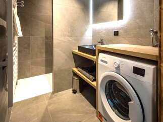This modern bathroom features a sleek design with a washing machine, a stylish sink, and ample storage space.