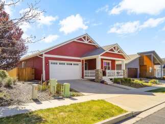 This stunning red house boasts a charming porch and a spacious garage, perfect for modern living.