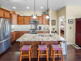 This stunning kitchen boasts beautiful wooden cabinetry and a spacious island with a granite countertop, perfect for meal preparation and entertaining.