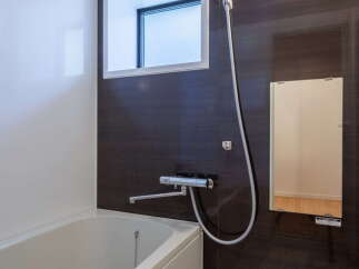 This modern bathroom features a sleek design with a bathtub, showerhead, and a stylish dark wood-paneled wall.