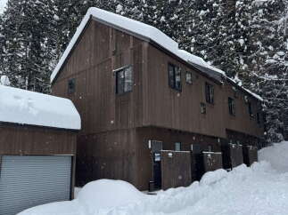 This stunning property boasts a modern design with a warm, inviting wooden exterior, perfect for a cozy winter retreat.